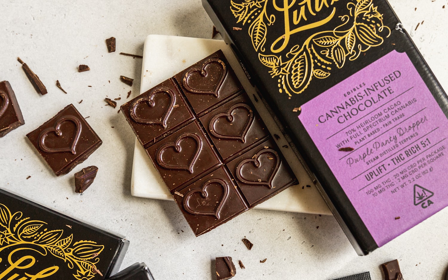 A licensed cannabis-infused chocolate bar scored into squares beside its box, showing THC and CBD amounts per package and per square