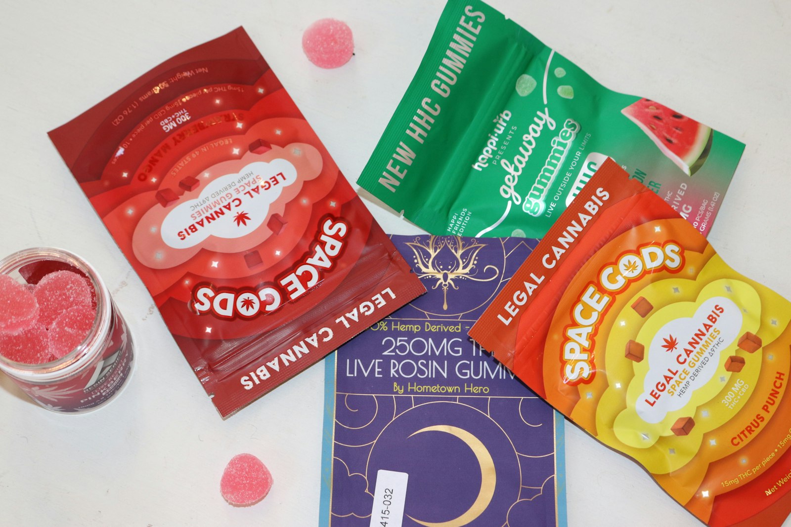 Several sealed edible gummy packages printed with milligram totals, per-piece potency and a batch number sticker