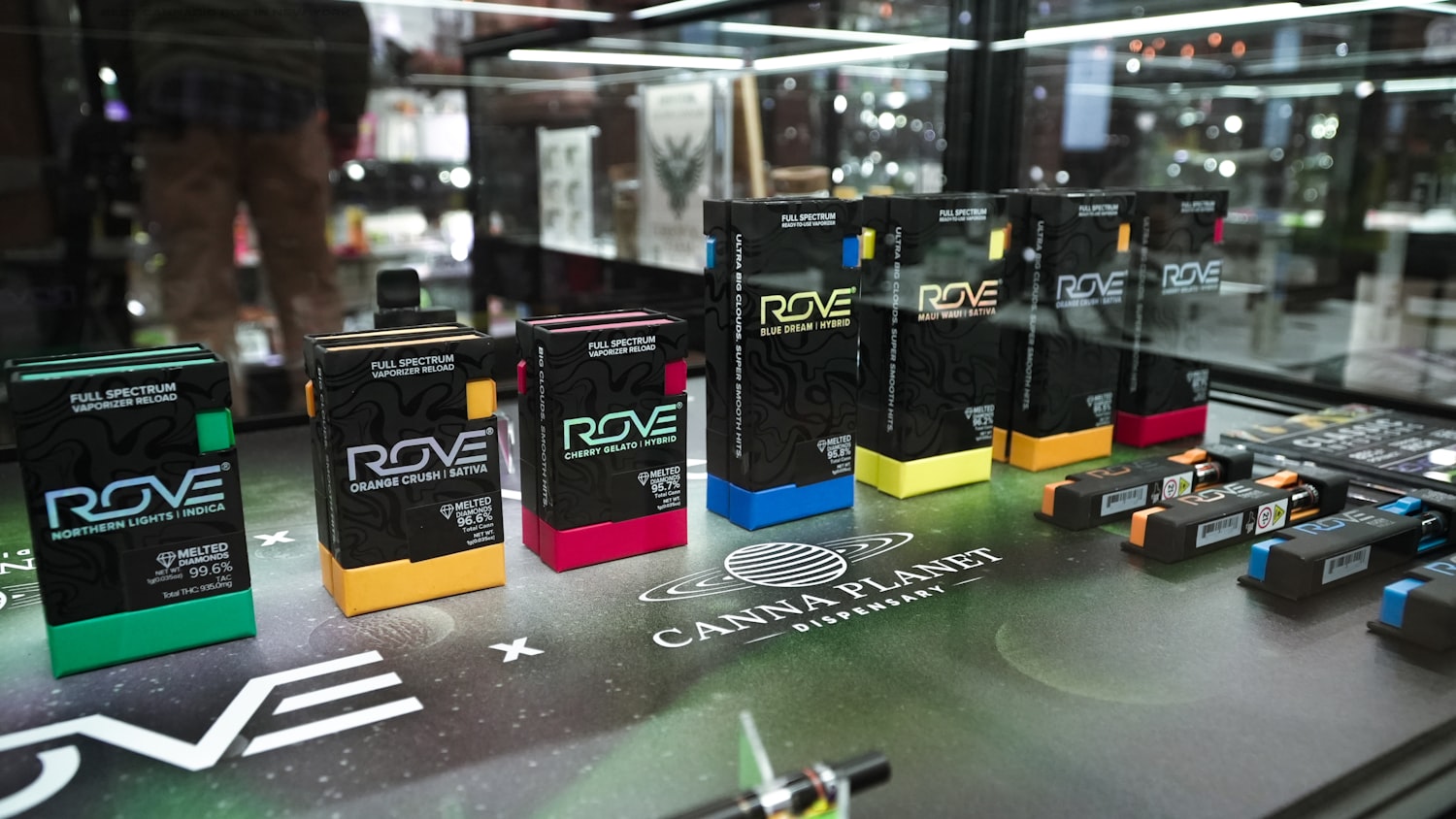 A licensed cannabis retail display case filled with vape cartridges and packaged products