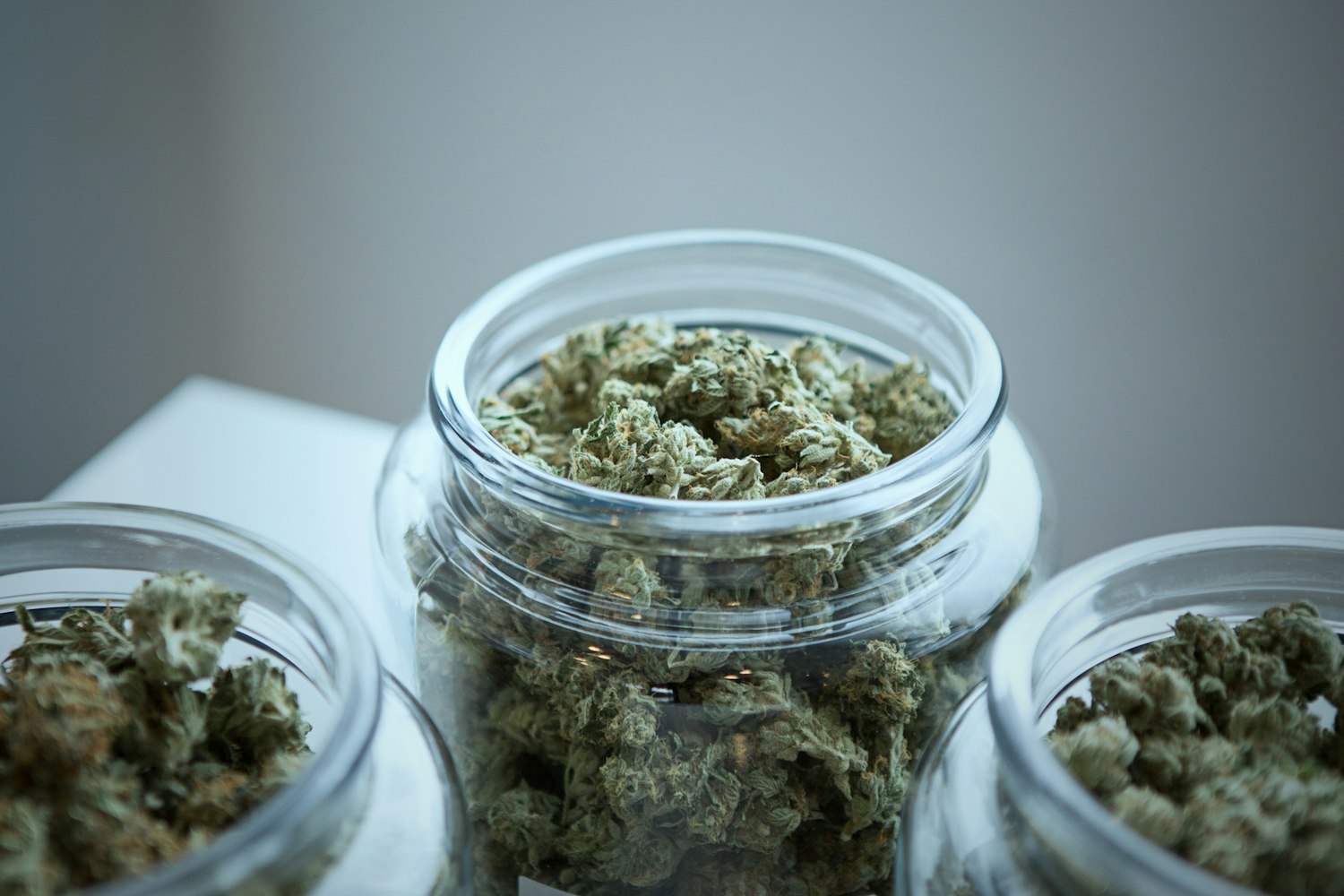 Cannabis flower stored in a sealed clear glass jar on a dark surface