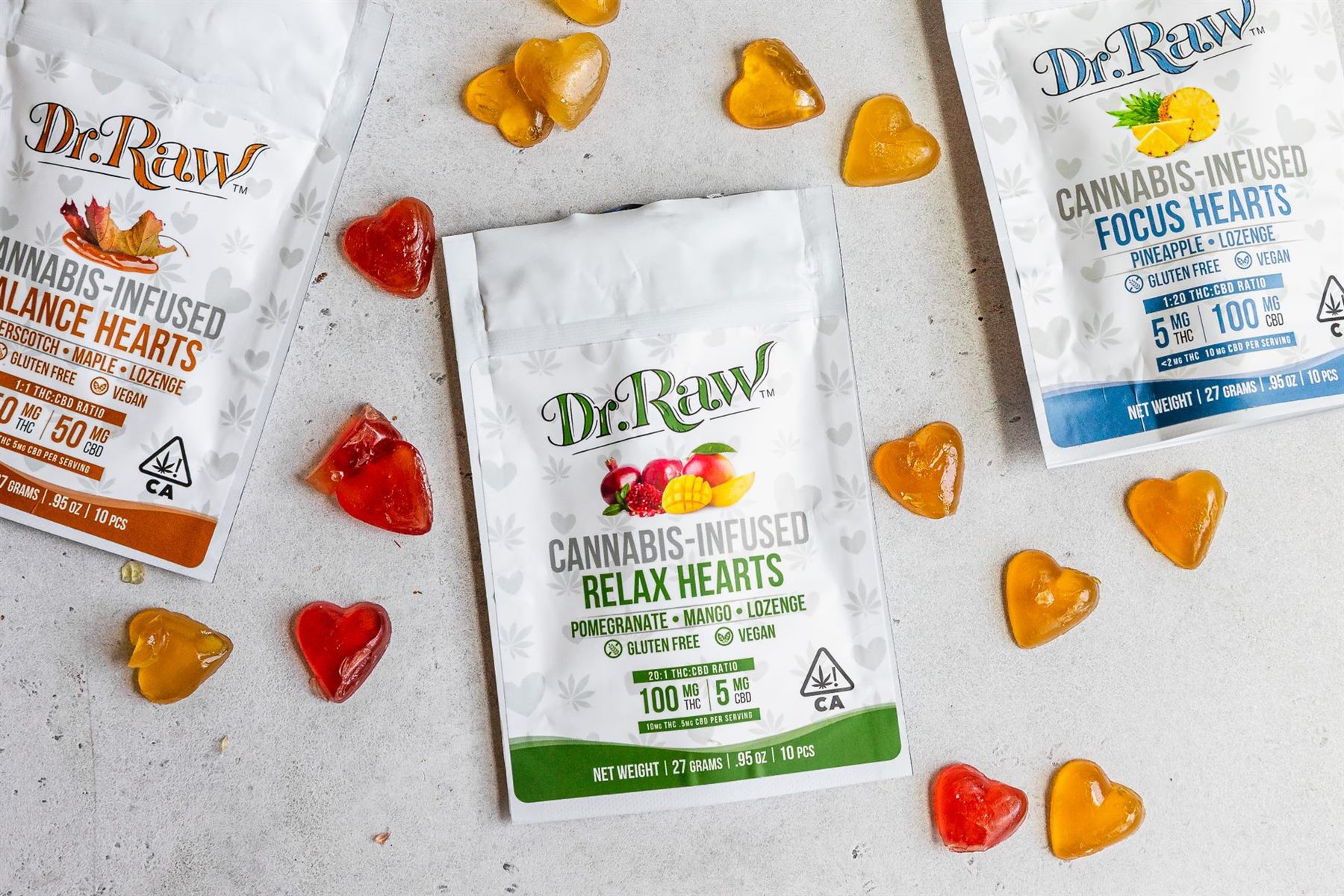 Heart-shaped cannabis gummies scattered around packages showing THC and CBD milligram amounts