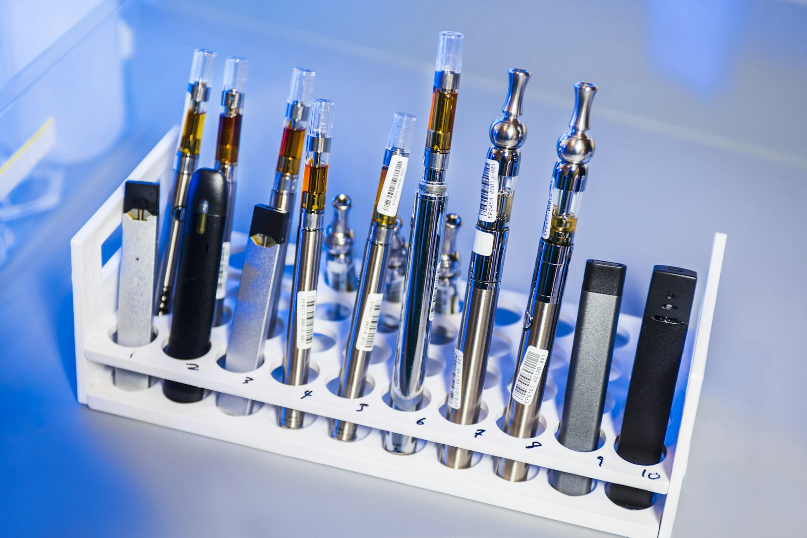 A rack holding a row of vape cartridges and battery devices lined up side by side