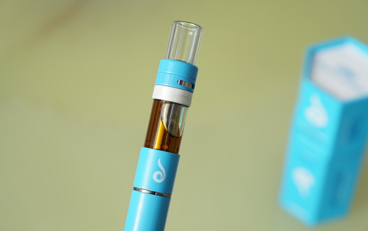 Close-up of a cannabis vape cartridge showing amber oil behind glass and a clear mouthpiece