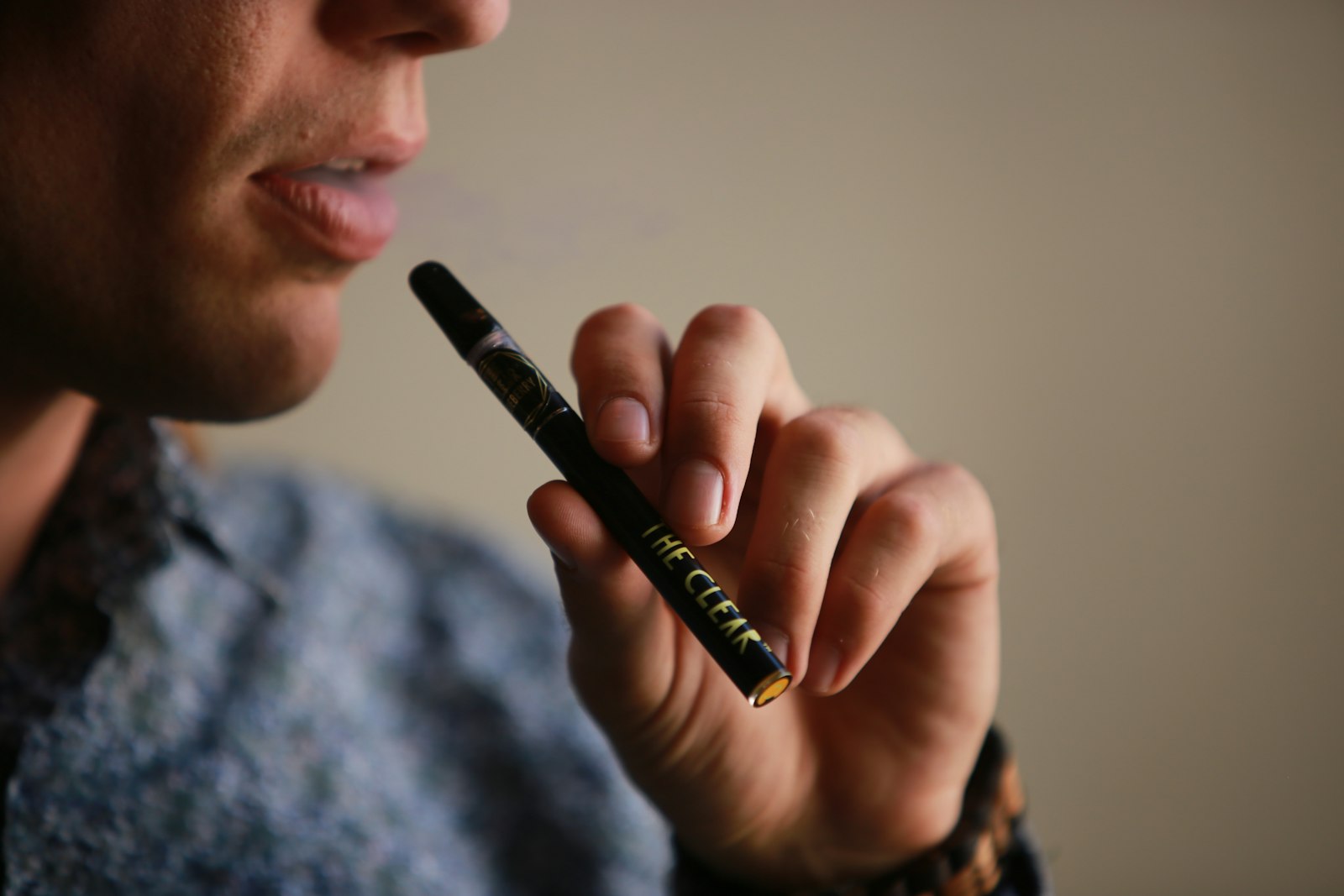 A person taking a short draw from a slim cannabis vape pen